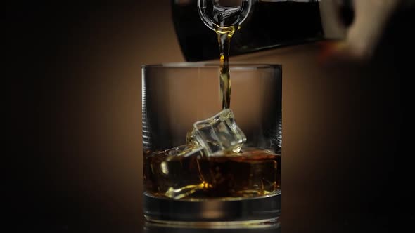 Pouring Whiskey, Cognac Into Glass. Dark Background. Pour of Alcohol Drink