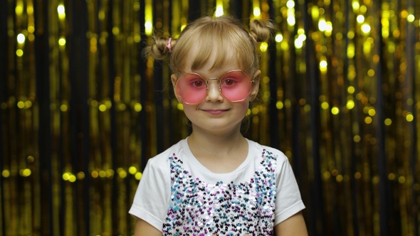 Child Show Ok Sign, Smiling, Looking at Camera. Girl Posing on Background with Foil Golden Curtain