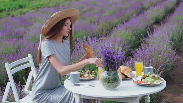 Young Woman Eating Croissant in Lavender Field