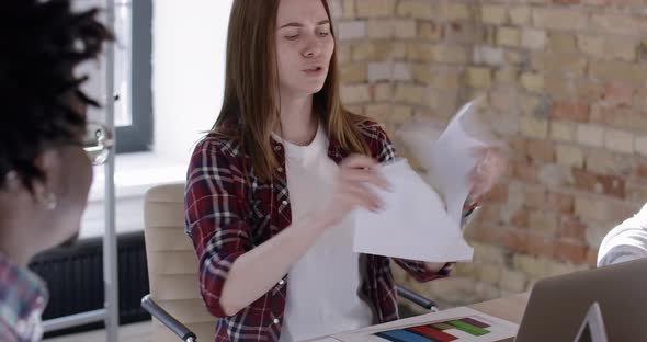 Portrait of Nervous Young Beautiful Woman Tearing Papers in Office. Dissatisfied Caucasian Employee