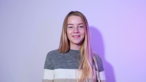 A Shot of a Blond Girl Against a Bright Background Pointing Her Fingers Up and Smiling