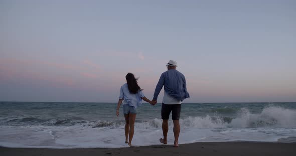 Exciting Couple Walks Along Sandy Beach To Endless Ocean