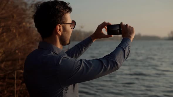 Man Taking Photo On Vacation In Resort. Man Takes Pictures On Smartphone On Seashore. Video Call.