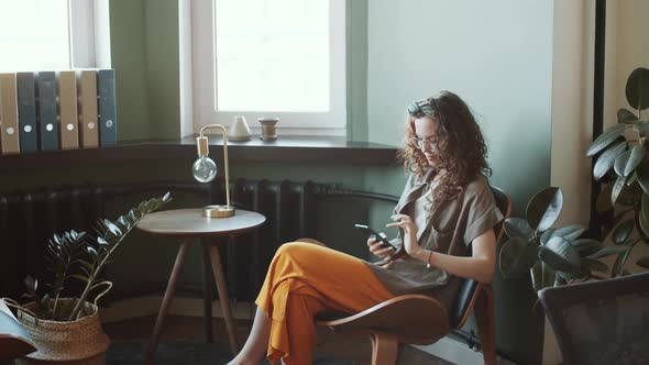 Young Woman Using Smartphone in Office Lounge Area