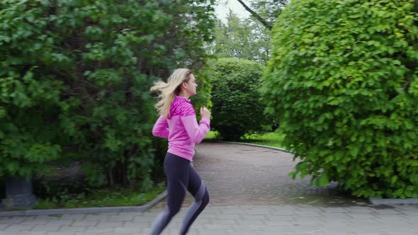 Fit Girl Runs Along City Park