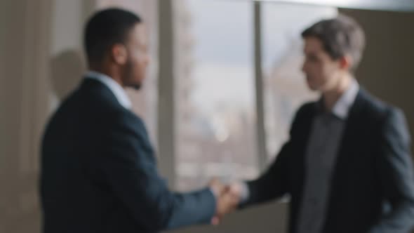 Blurred Two Multiracial Multinational Businessmen Talking in Office Shaking Hands Unfocused View