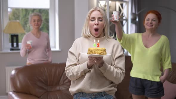 Beautiful Caucasian Adult Woman Wishing Blowing Out Candles on Birthday Cake on 42 Birthday Smiling