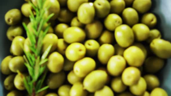 Fresh green olives and rosemary in a bowl