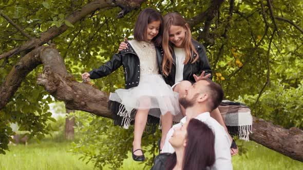 Handsome Husband Embracing His Pregnant Wife While Their Two Daughters Sitting