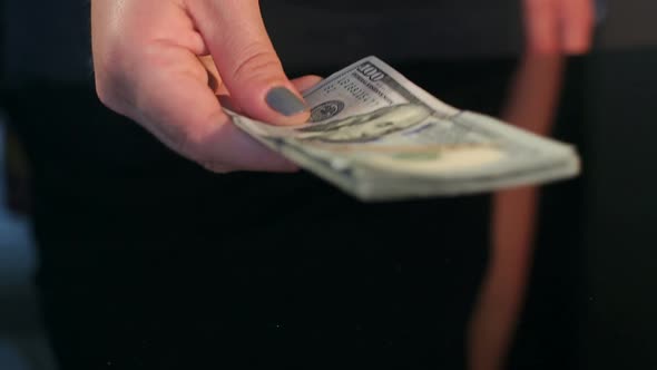 Closeup of Girl Gives a Stack of Dollars to Man