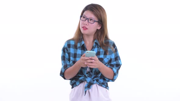 Happy Young Asian Hipster Woman Thinking While Using Phone