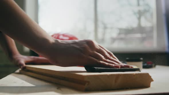 Woman Builder Sanding Wooden Board with Sandpaper