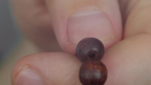 Close Up of a Young Man's Hand, Fingering a Wooden Rosary