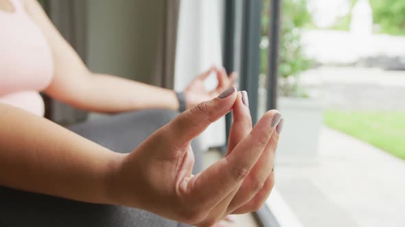 Video of hands of plus size african american woman exercising at home, practicing yoga