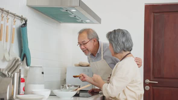 Asian senior grandfather cook salad dish with grandmother with happiness and smile enjoy retirement.