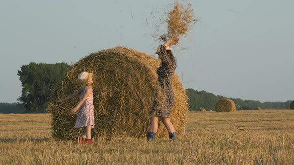 Little Girl with Mom Having Fun Next to Hay Bale