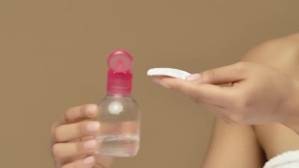 Beauty Portrait of Young African American Woman Pouring Lotion Onto Cotton Pad and Cleansing Face