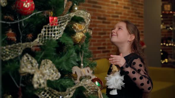 Child girl put toy on christmas tree at home