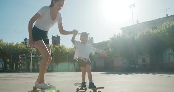 Mother Teaches Her Daughter to Ride on Skateboard