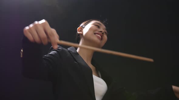 Asian Conductor Woman Holding A Baton Closing Her Eyes And Showing Gesture In The Black Studio