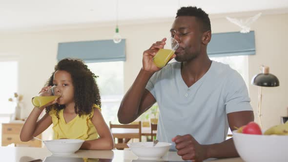 African american father and daughter drinking juice at home
