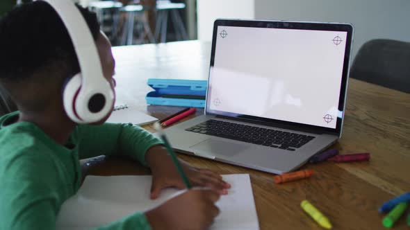 African american boy having a video call on laptop with copy space while doing homework at home