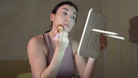 Woman applying make-up, looking in mirror