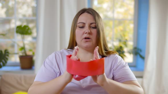 Portrait of Fat Woman Trying To Lose Weight at Home Doing Exercises with Expander