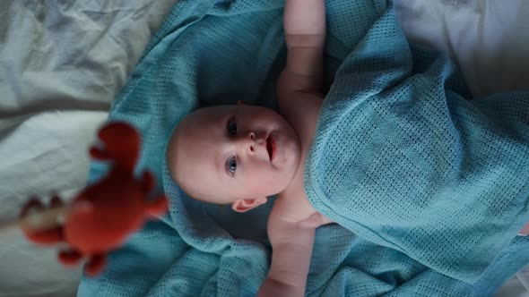 Little Cute Causian Baby Boy Smiling at Camera Boy Looks at the Toy and is Delighted