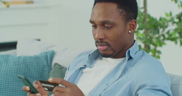 Portrait of Young African Man Relaxing at Home Shopping Online with Credit Card