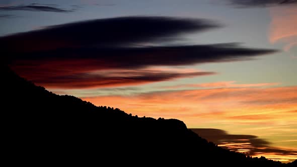Sunset over mountains. Time-lapse of sun setting over the mountains. Sequence of clouds dissipating.