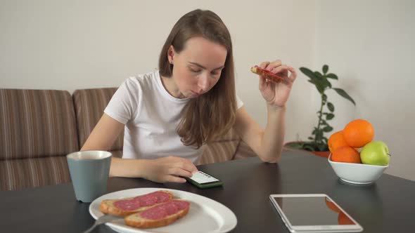 Woman Using a Smartphone at Home in a Modern Kitchen