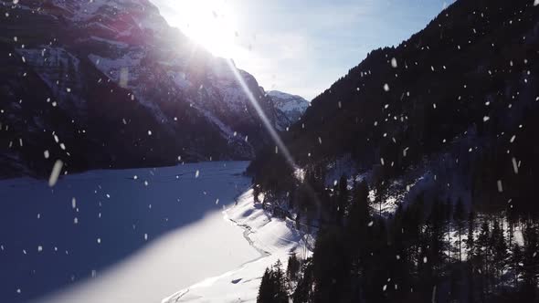 Frozen lake water covered in snow near majestic mountain ranges, aerial drone view