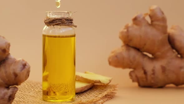 Glass Bottle of Essential Ginger Oil Ginger Root on Beige Background