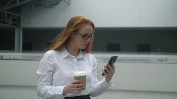 businesswoman in business clothes, walks through business center with coffee.