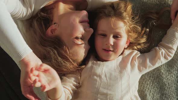 Top view of attractive young woman with little cute girl waving hand to the camera are spending time