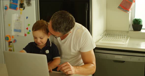 Father and Son Using Laptop in Kitchen 4k