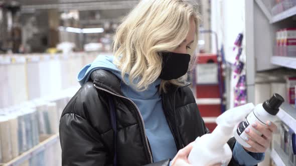 A Woman in a Protective Mask Chooses a Product in a Supermarket