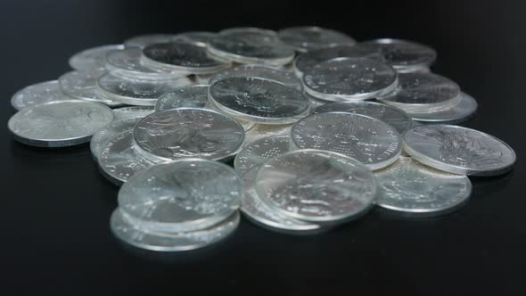 Gold coins being dropped on pile of silver coins