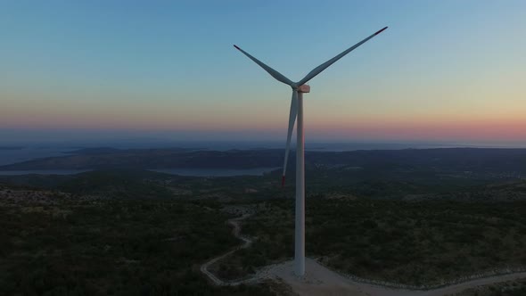 Flying above elegant white windmill at sunset