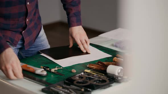 The Process of Manufacturing a Leather Wallet Handmade. The Wizard Makes a Mark on the Leather Bark