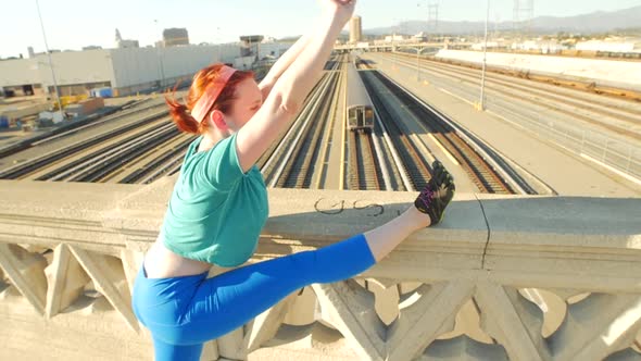 A young woman stretching before working out in urban environment.