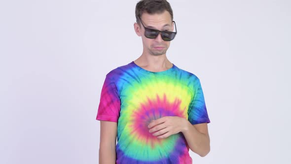 Studio Shot of Man with Tie-dye Shirt Waking Up After Heavy Partying