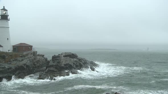 Pan across foggy, rainy seascape at Portland Head Light.