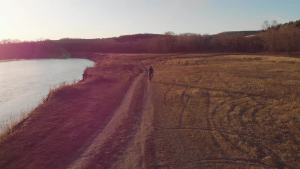 Aerial View of a Cyclist Riding on His Bicycle in Mountain at Sunset.