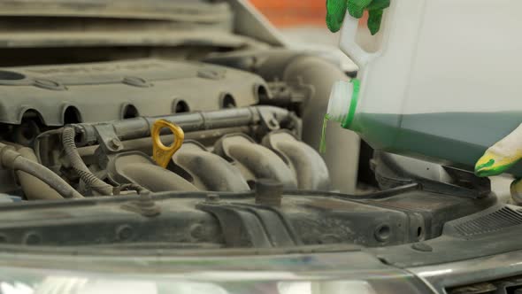 Man Hands in Work Gloves Pours Brake Fluid in Car Closeup