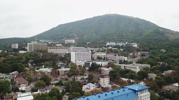 Aerial view on the small Russian town on the background of the hill. Trees along with houses. Drivin