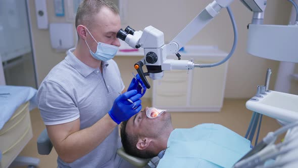 Side View Male Caucasian Dentist Using Dental Endodontic Binocular Microscope Examining Oral Cavity