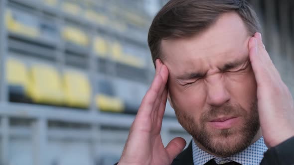 An Office Worker Has a Headache He is Sitting on a City Street