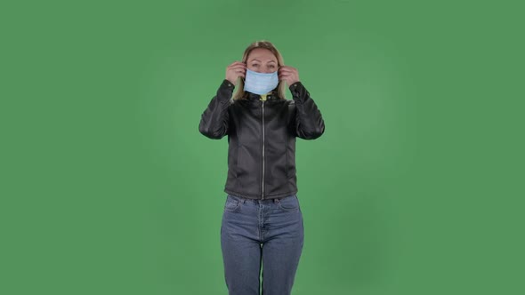 Portrait of Beautiful Young Woman Puts on Medical Mask, Blonde with Loose Hair in a Black Jacket